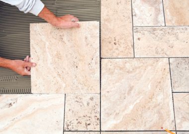 worker-places-new-tile-on-a-bathroom-floor-travertine worker-places-new-tile-on-a-bathroom-floor-travertine